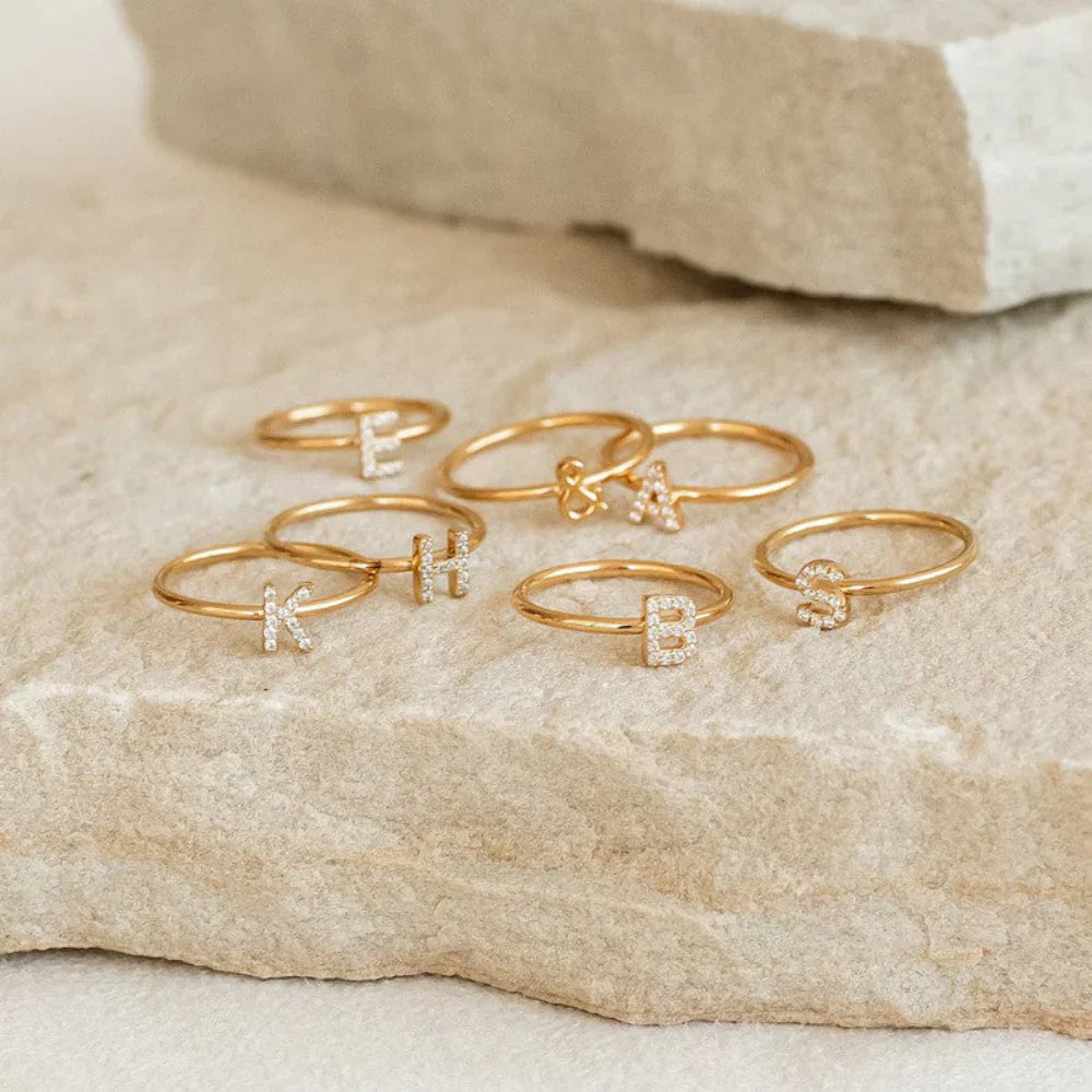 isplaying a trendy ring stack featuring the Custom Pavé Diamond Initial Ring.