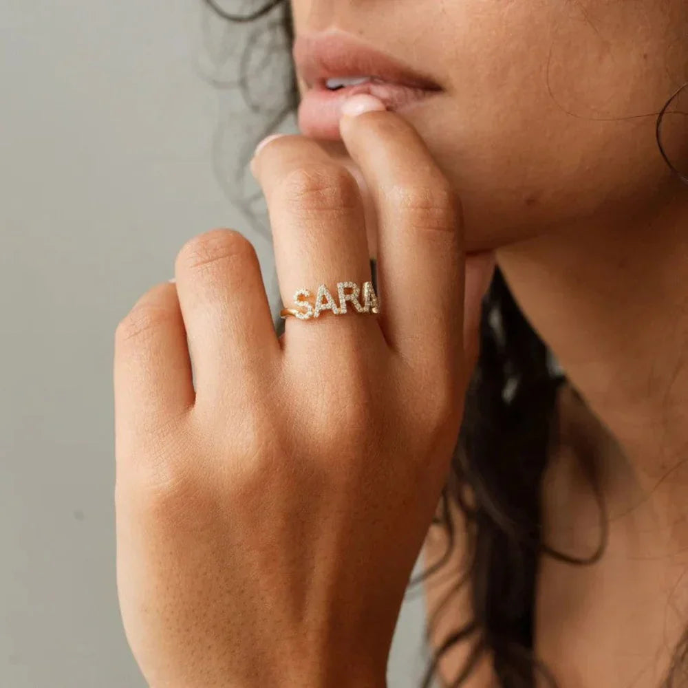 Model displaying gold Custom Diamond Name Ring with name script and diamond accents.