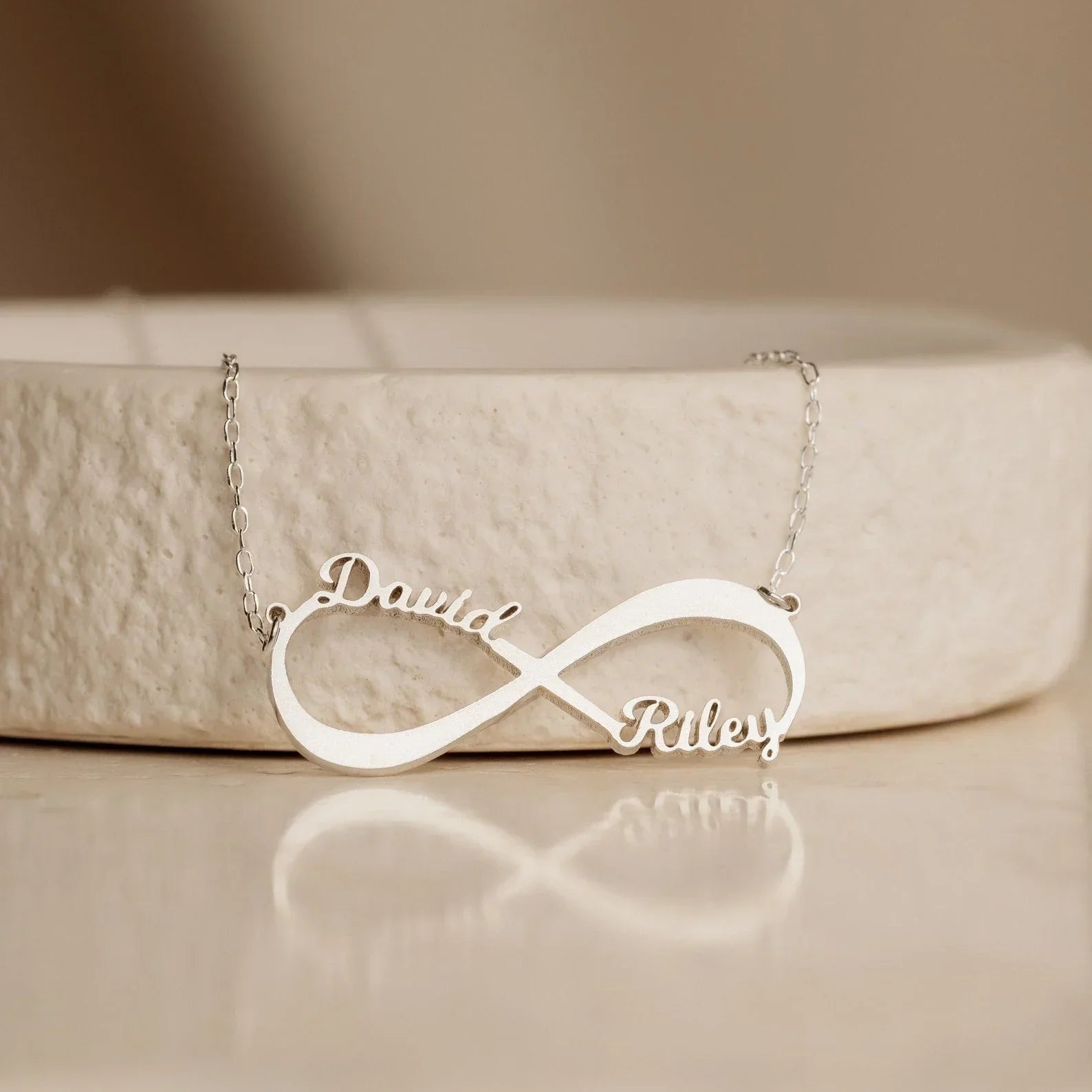 Close-up of the Personalized Name Infinity Necklace in gold, showcasing custom engraved names on a sleek infinity symbol