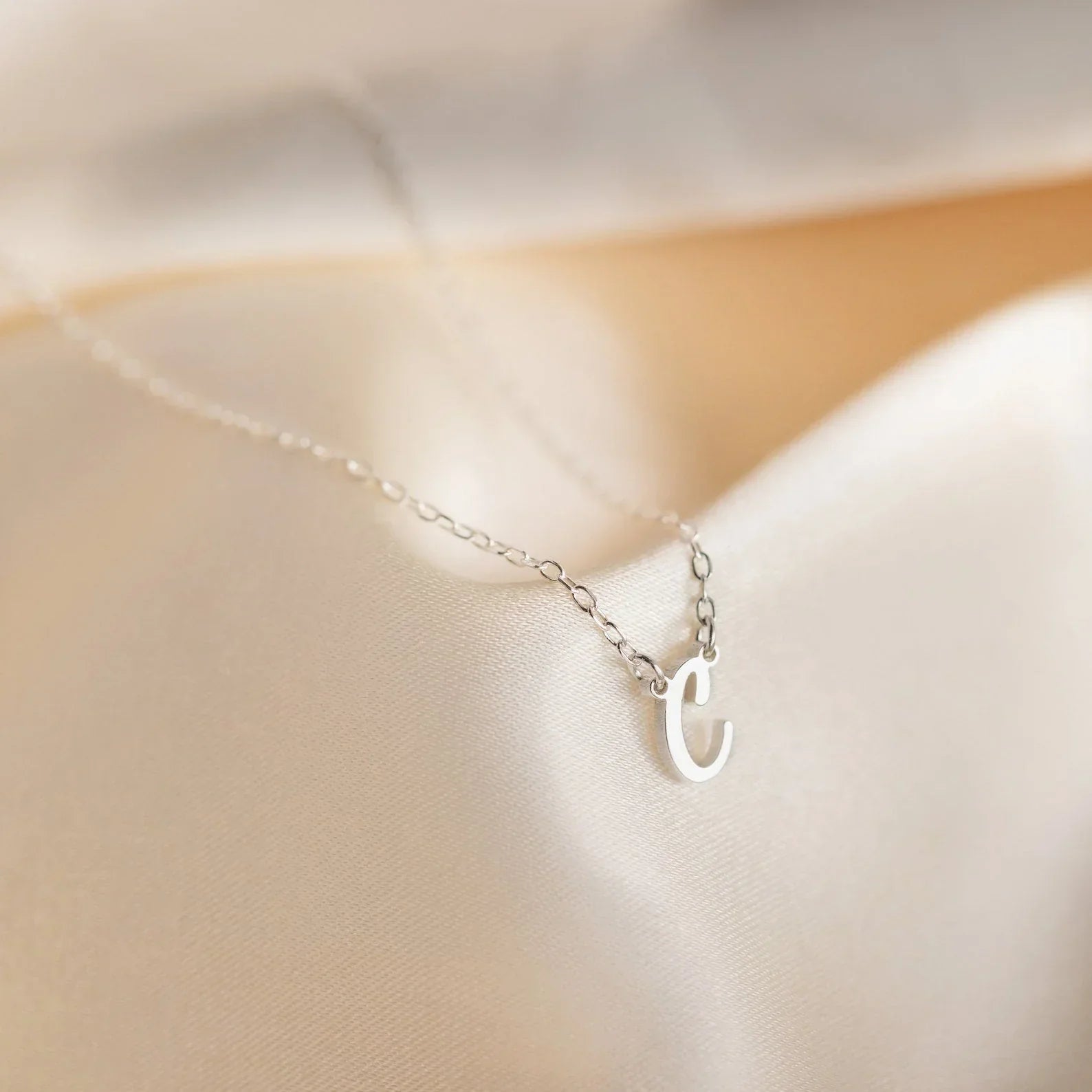 Eraya Jewel Initial Letter Pendant showcasing the letter 'C,' highlighting its elegant and minimalist design. The pendant is displayed to emphasize its delicate form and the clarity of the letter.