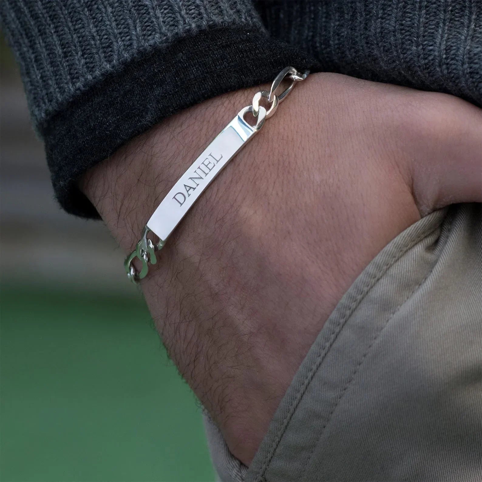Close-up of a model wearing the Eraya Jewel Custom Engraved Men's ID Bracelet in Silver, focusing on the detailed personalization.