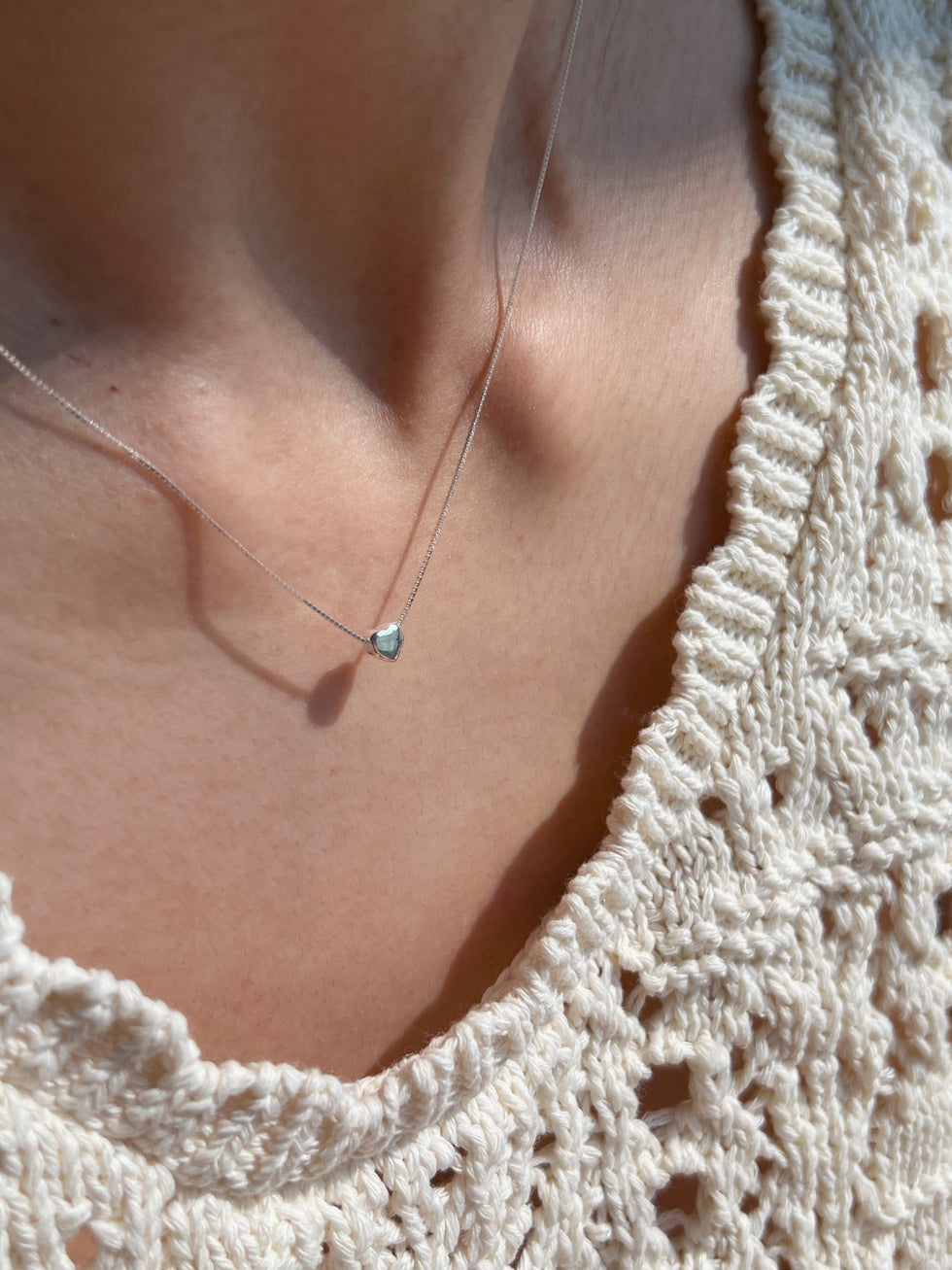 Model wearing a dainty silver heart necklace styled with a soft, feminine look for a subtle romantic vibe.