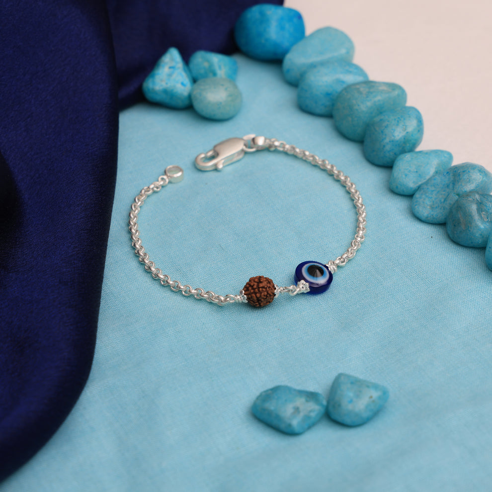 Close-up of Rudraksha bracelet with blue evil eye charm and sterling silver detailing, symbolizing protection and warding off negativity.

